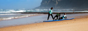 1 day surf lessons on a empty beach portugal. Surfer girls learn surf technique, on the sand in front of the ocean.