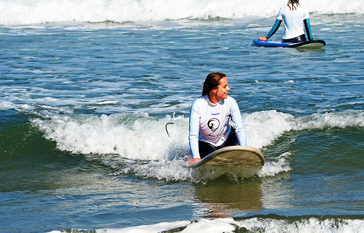 surfer girl rides wave on atlantic coast surf school surf lesson in Praia Azul - Santa Cruz, ocean, sunshine, nature
