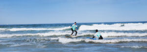 Surfer rides wave on the surf lesson in Praia Azul - Santa Cruz, surfer girl watches, good waves