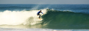 Surfer on a green wave in Praia Azul - Santa Cruz, Portugal during surf lesson. Sunshine and clear water