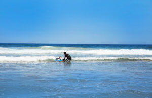 surfer girl with surf instructor catches one wave on the private surf course. In Portugal with Atlantic Coast Surf School